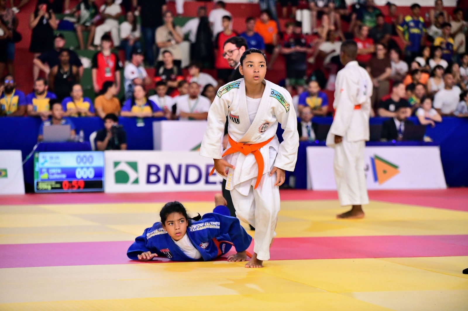Lídia Sayuri em pé no tatame com a adversária no chão, durante luta do Campeonato Brasileiro Sub-13