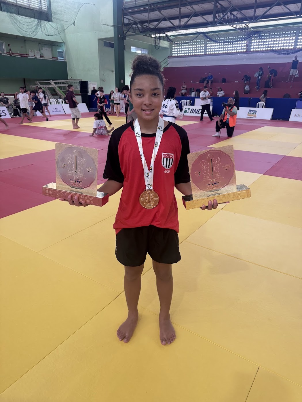 Lídia Sayuri com a medalha de ouro e os dois troféus de primeiro lugar da equipe paulista