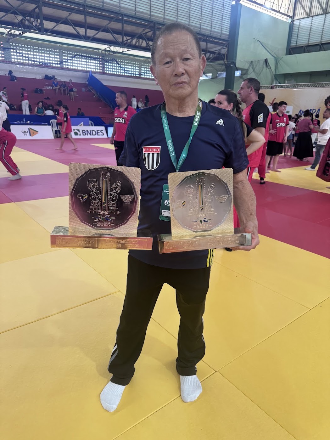 Sensei Sergio Honda segurando os dois troféus de primeiro lugar conquistados pela seleção paulista