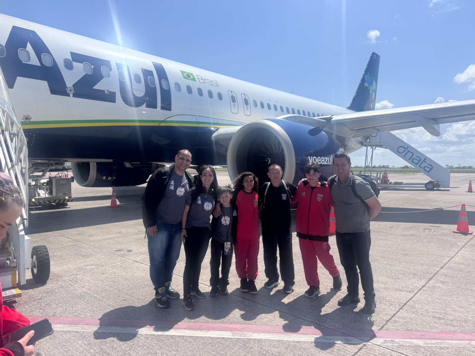 Lídia, Davi, Sensei Sergio Honda e as famílias posando ao pé do avião, na pista