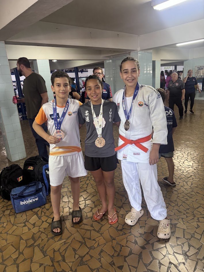 Matheus Tortelli e Giovana Tortelli ao lado da Lídia Sayuri, todos com medalhas, na Copa Amparo 2026