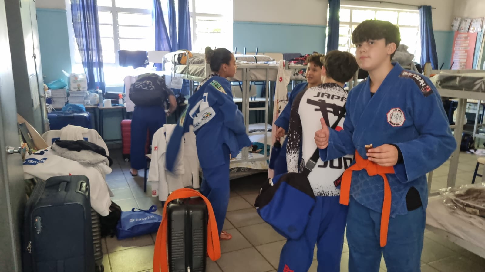 Atletas da delegação Honda no dormitório alugado com kimonos azuis se preparando para o treino da tarde