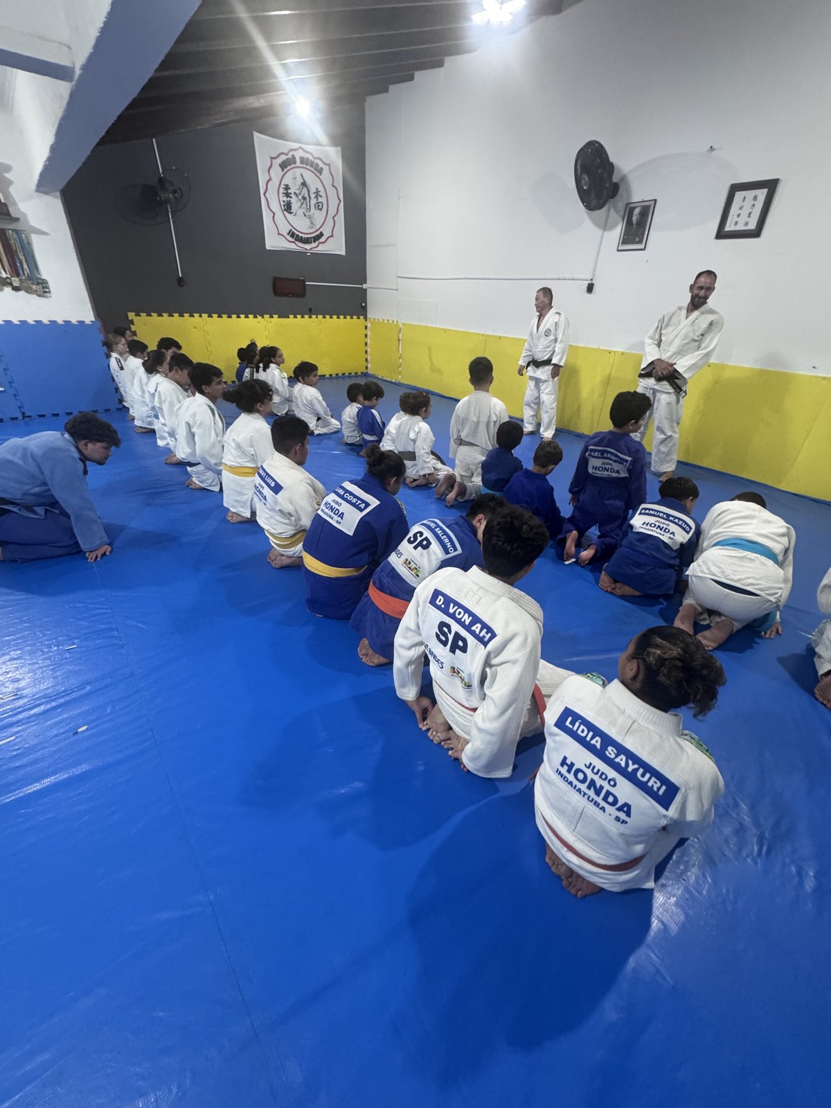 Sensei conduzindo o treino no tatame do Judô Honda com os alunos sentados em fila