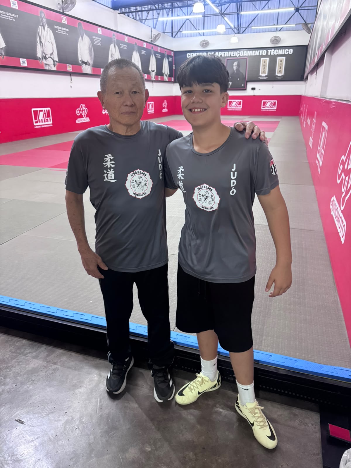 Sensei Sergio Honda e o atleta Davi Von Ah Camargo com a camiseta do Judô Honda Indaiatuba na beirada do tatame do Centro de Aperfeiçoamento Técnico